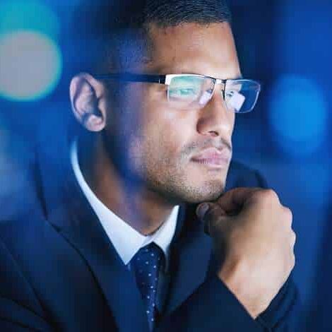 Business, office and man thinking, planning and problem solving at night in a corporate company. Serious and focused male employee in networking, big data and technology for digital innovation